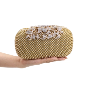 Detailed view of luxury gold rhinestone evening clutch with leaf clasp held in hand