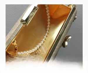 Détail de la pochette de soirée à paillettes dorées avec doublure en satin et perles