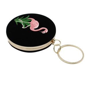 Macro-opname van ronde fluwelen clutch met flamingo-borduurwerk en met diamanten bezette ring