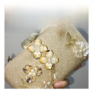 Détail d'une pochette dorée de soirée avec fleurs 3D, perles et feuilles d'or
