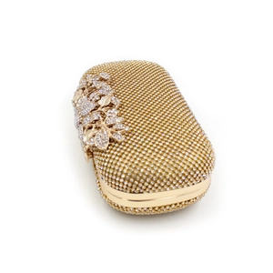 Close-up of golden evening clutch featuring crystal leaf decor and full rhinestone surface