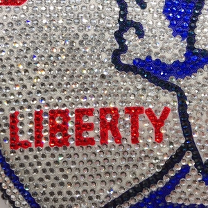 Close-up of sparkling multicolor rhinestones and Liberty text detail on an evening bag
