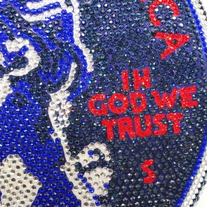 Macro view of crystal rhinestones showing IN GOD WE TRUST text on a round clutch