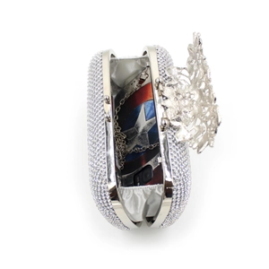 Detail view of rhinestone evening clutch showing silver floral clasp and internal capacity