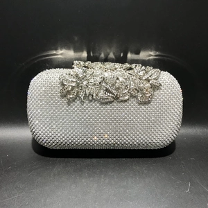 Detailed close-up of sparkling crystals and floral leaf metal clasp on silver evening clutch