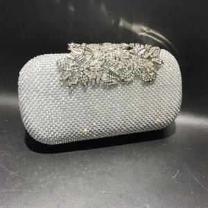 Close-up of silver evening bag featuring crystal rhinestones and floral leaf clasp detail