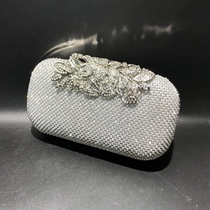 Detailed view of silver crystal rhinestones and floral metal ornaments on dinner clutch bag