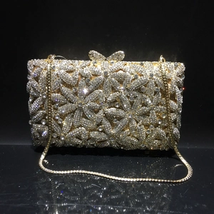 Detailed view of silver crystal evening bag with floral pattern and golden bow clasp