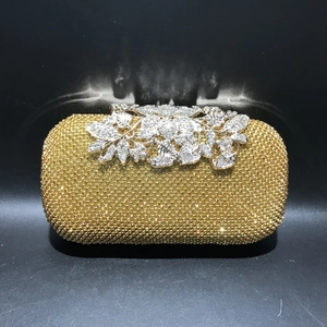 Close-up of sparkling gold evening clutch with leaf crystal clasp and rhinestone mesh detail