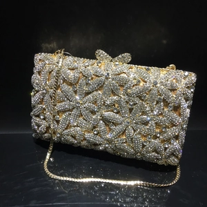 Macro detail of gold evening clutch featuring crystal floral patterns and butterfly clasp