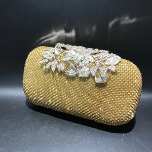 Macro shot of silver floral clasp and sparkling gold rhinestones on luxury evening clutch