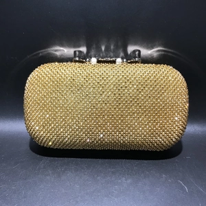 Close-up of golden crystal evening clutch with sparkling rhinestones and metal clasp