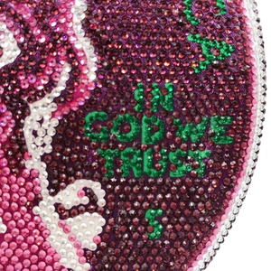 Macro shot of colorful rhinestones with In God We Trust text on luxury dollar clutch bag