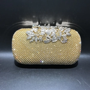 Macro shot of gold rhinestone evening bag with intricate silver leaf clasp detail
