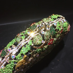 Détail de strass en cristal et motifs de feuilles en émail vert sur pochette de soirée