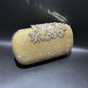 Detail of crystal rhinestones and silver leaf clasp on gold evening clutch bag
