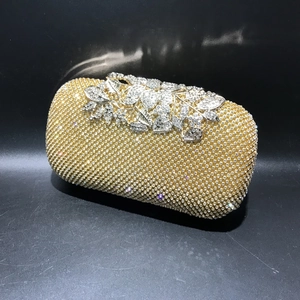 Close-up of gold rhinestones and decorative silver flower floral cluster on evening clutch