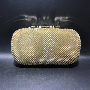 Macro shot of sparkling white rhinestones and gold clasp on leaf pattern evening bag