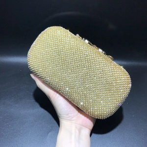 Detailed close-up of a gold crystal clutch bag held in hand for evening party gala