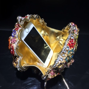 Luxurious floral crystal clutch showing interior space with a smartphone for scale