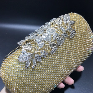 Close-up of gold evening clutch featuring rhinestone leaf pattern and glittering crystals