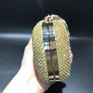 Side close-up of a gold crystal evening clutch with leaf pattern and rhinestone inlay