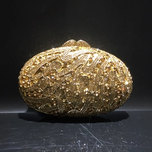 Detail of golden rhinestone evening clutch with intricate spiral cutout and crystal inlay