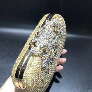 Close-up of sparkling gold evening clutch with crystal flowers held in hand