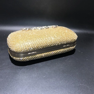 Macro view of gold evening clutch featuring full rhinestone mesh and metal clasp detail