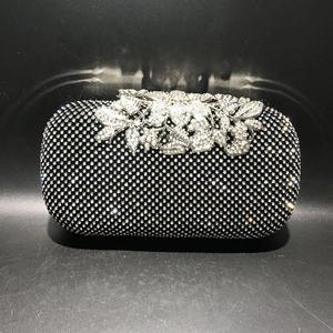 Macro shot of silver crystal leaf clasp on a black rhinestone evening clutch bag
