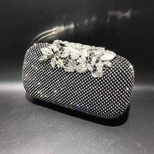 Close-up of black crystal evening bag featuring silver leaf-shaped rhinestone clasp