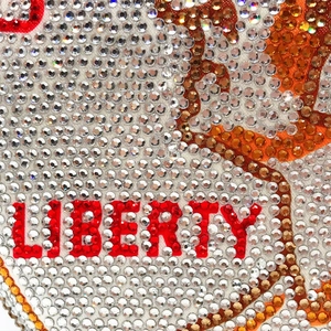 Macro view of Liberty lettering crafted from red and clear rhinestones on evening clutch