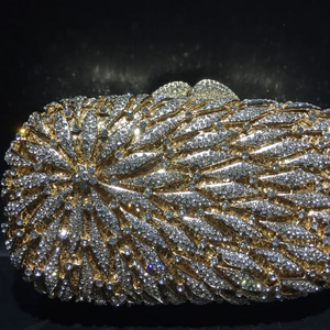 Gros plan détaillé de la pochette de soirée dorée avec motifs de plumes en cristal