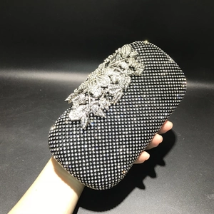 Detail view of a black dinner clutch bag encrusted with sparkling rhinestones and silver leaf accents