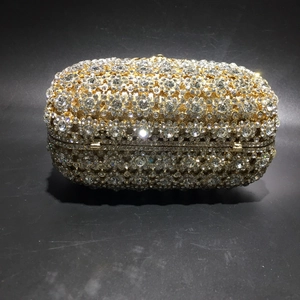 Detailed close-up of golden oval evening clutch bag with sparkling floral crystal patterns