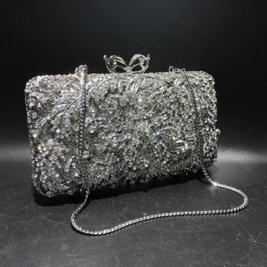 Close-up of sparkling silver crystal clutch bag with intricate flower texture and bow clasp