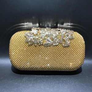 Close-up of golden rhinestone evening bag with elegant silver leaf-shaped clasp