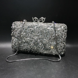 Macro detail of silver clutch with rhinestone vine patterns and butterfly clasp lock
