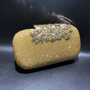 Close-up of golden evening clutch featuring crystal rhinestones and metal leaf clasp