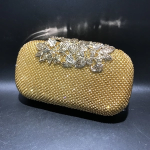 Close-up of golden rhinestone evening bag featuring silver leaf and floral metal clasp