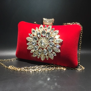 Detailed macro view of a red velvet evening bag with a large sunflower rhinestone brooch