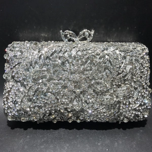 Detailed view of silver crystal evening clutch with hollow floral patterns and butterfly clasp