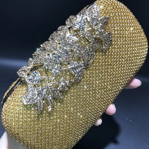 Macro detail of golden evening clutch bag with crystal leaf floral relief and rhinestones