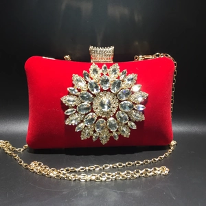 Close-up of red velvet evening bag featuring sparkling rhinestone sunflower and gold chain