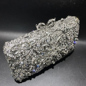 Detailed shot of silver evening bag with crystal scroll patterns and bow clasp closure