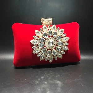 Macro shot of red velvet evening bag featuring a large sparkling rhinestone sunflower