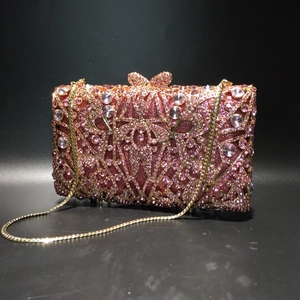 Close-up of pink crystal clutch with rose gold rhinestones and bow clasp detail