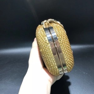 Detail of hand holding luxury gold rhinestone evening clutch with crystal leaf pattern