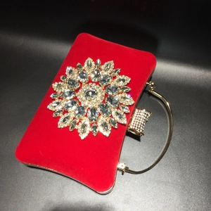 Detailed view of red velvet evening bag with crystal sunflower and gold handle