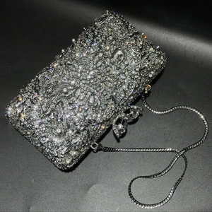 Close-up of silver crystal evening clutch with hollow floral pattern and butterfly clasp